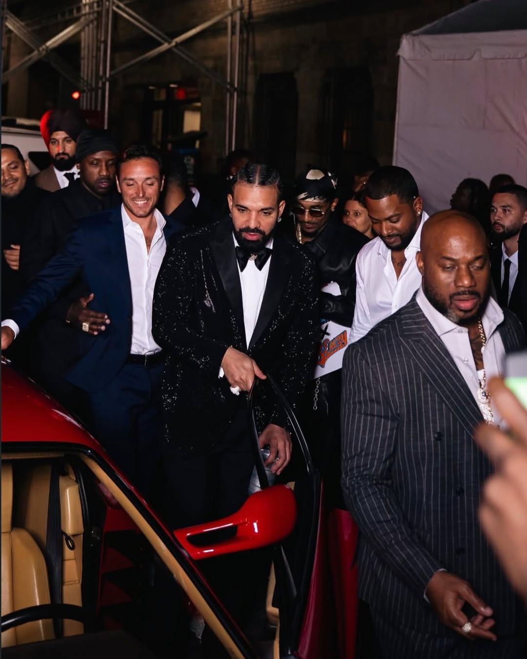 Drake at a New York night event beside a red sports car during 40th birthday coverage