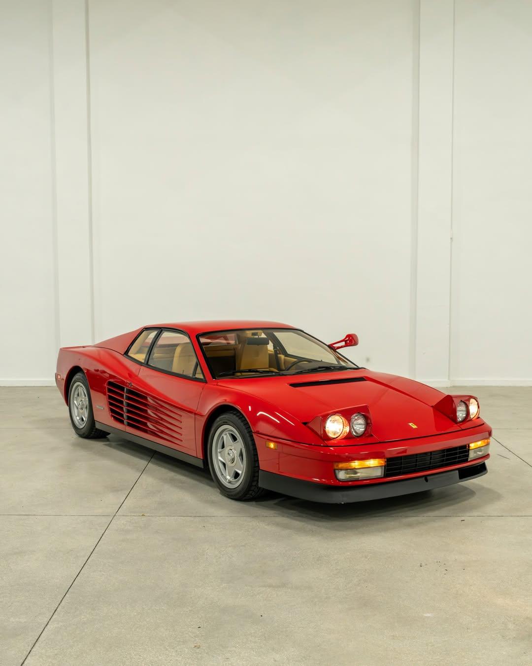 Red Ferrari Testarossa in a studio, showing low ground clearance and side strakes